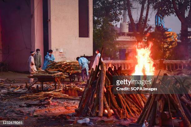 People perform the last rights of a relative who has died of Covid-19 coronavirus disease as other funeral pyres are seen burning during a mass...