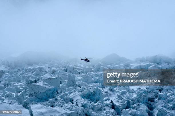 In this photograph taken on May 2, 2021 an helicopter flies over Khumbu glacier in the Mount Everest region of Solukhumbu district, some 140 km...