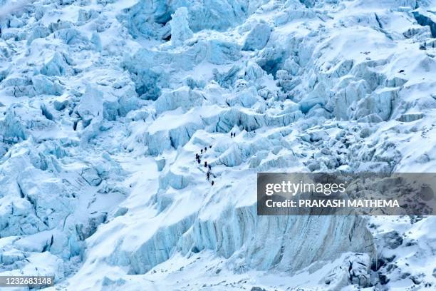 In this photograph taken on May 2, 2021 mountaineers trek along the Khumbu glacier near Everest base camp in the Mount Everest region of Solukhumbu...