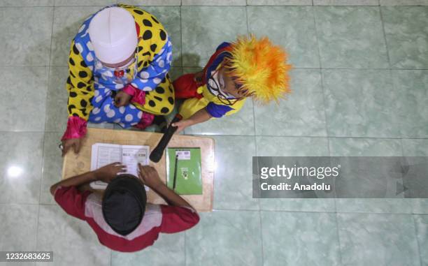 Yahya Edward Hendrawan accompanied by his son Mirza wears a clown costume teaches the Quran at the Darussalam An-Nur Foundation in Tangerang, Banten...