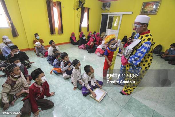 Yahya Edward Hendrawan accompanied by his son Mirza wears a clown costume teaches the Quran at the Darussalam An-Nur Foundation in Tangerang, Banten...