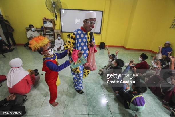 Yahya Edward Hendrawan accompanied by his son Mirza wears a clown costume teaches the Quran at the Darussalam An-Nur Foundation in Tangerang, Banten...