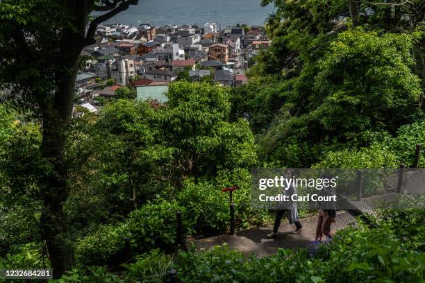 Women wearing face masks walk through a garden in the grounds of a Shinto shrine on May 4, 2021 in Kamakura, Japan. As Japan enjoys its annual Golden...