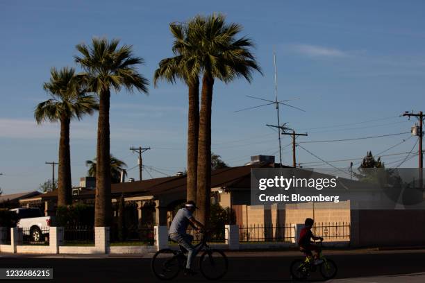 People ride their bicycles through a neighborhood in Phoenix, Arizona, U.S., on Saturday, April 24, 2021. The U.S. Economy is on a multi-speed track...