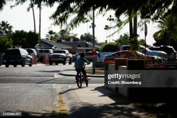 Child rides a bicycle through a neighborhood in Phoenix, Arizona, U.S., on Saturday, April 24, 2021. The U.S. Economy is on a multi-speed track as...