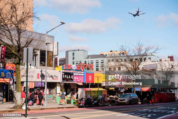 An airplane flies over stores on Main Street in the Flushing neighborhood in the Queens borough of New York, U.S., on Monday, March 29, 2021. The...