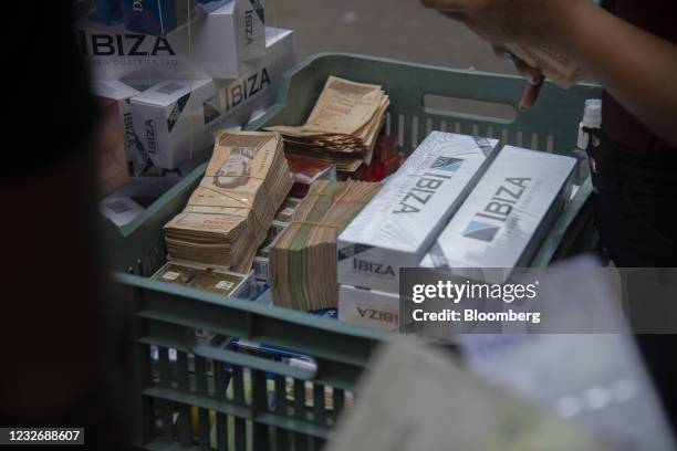 Basket of bolivar banknotes and Ibiza brand cigarettes in the Catia neighborhood of Caracas, Venezuela, on Thursday, March 25, 2021. The serious...