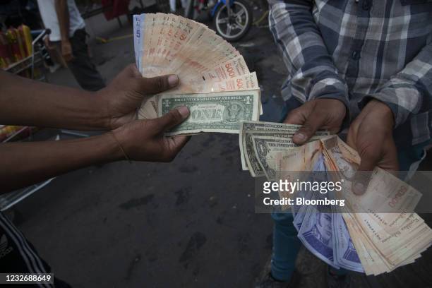 People hold U.S. Dollar and bolivar banknotes in the Catia neighborhood of Caracas, Venezuela, on Thursday, March 25, 2021. The serious side-business...
