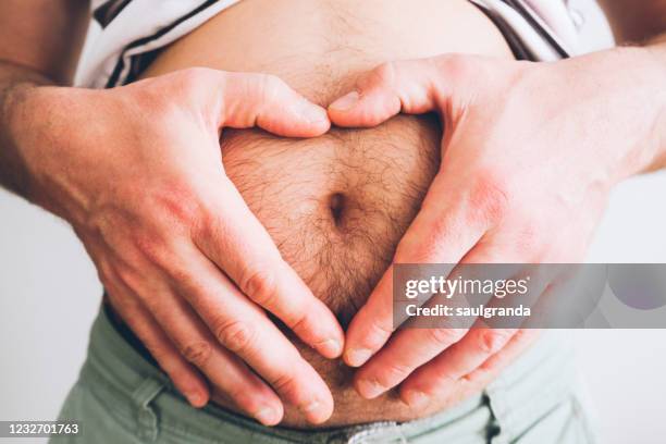 man with hands in heart shape on belly - behaart stock-fotos und bilder