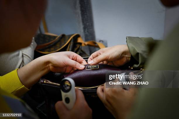 This picture taken on March 24, 2021 shows trainees practicing methods in verifying the authenticity of a handbag following a class at the...