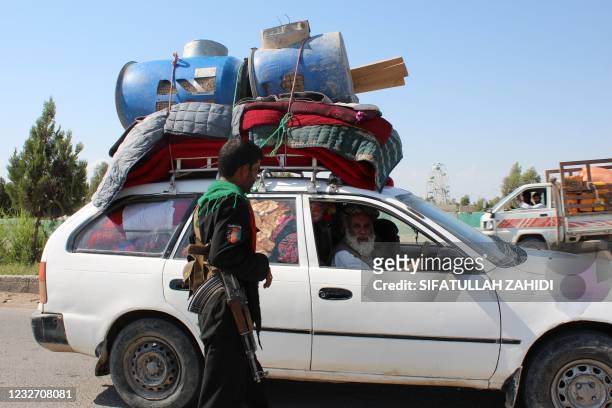 Policeman stands guard at a road checkpoint as an internally displaced family flees from the ongoing fighting between Afghan security forces and...