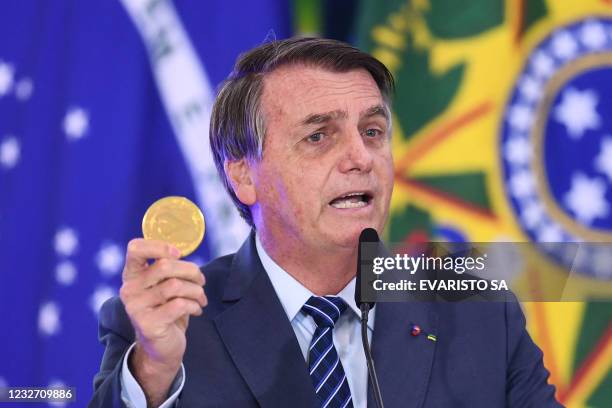 Brazilian President Jair Bolsonaro speaks and holds a Niobium coin during the launching event of the Week of Communication at the Planalto Palace in...