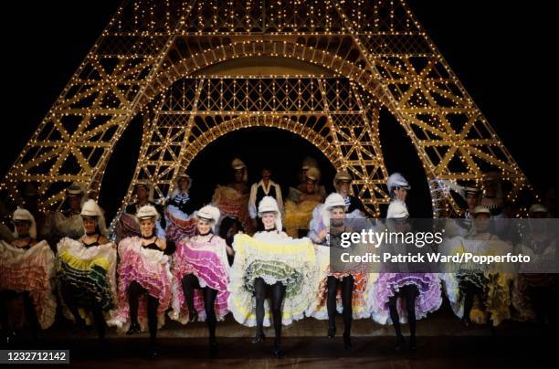 Dancers doing the can-can in traditional costumes in front of an illuminated Eiffel Tower during a Folies Bergere performance in Paris, France, circa...