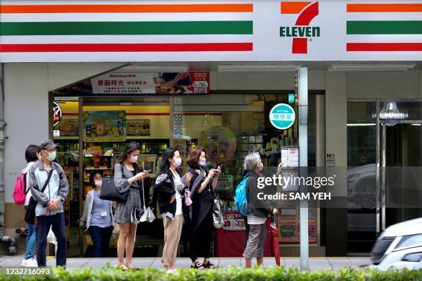 This picture taken on May 5, 2021 shows people waiting for buses in front of a 7-11 chain convenience store in Taipei.
