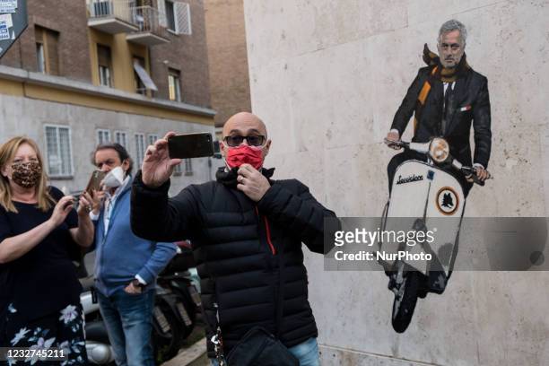 Man takes selfie in front of a mural by artist Harry Greb depicting the new coach of the AS Roma football team, Jose Mourinho riding a motor scooter,...