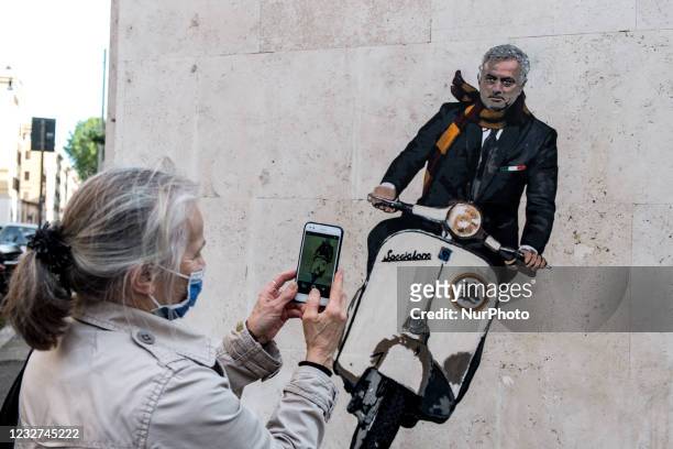 Woman takes a photot of a mural by artist Harry Greb depicting the new coach of the AS Roma football team, Jose Mourinho riding a motor scooter, on a...