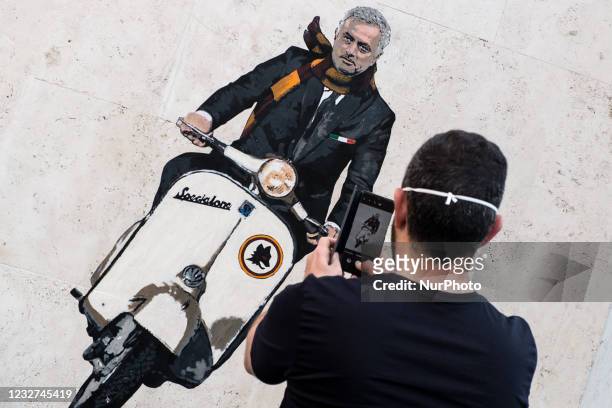 Man takes a photo in front of a mural by artist Harry Greb depicting the new coach of the AS Roma football team, Jose Mourinho riding a motor...