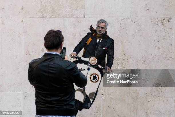 Man takes a photo of a mural by artist Harry Greb depicting the new coach of the AS Roma football team, Jose Mourinho riding a motor scooter, on a...