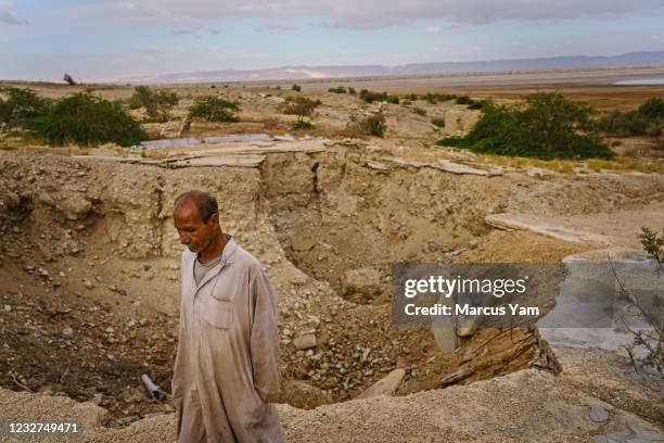 Hassan Kanazri, a 63-year-old tomato farmer, walks through the former grounds for the Numeira Salt company and where sinkholes have appeared, ground...