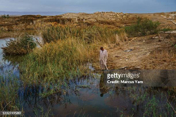 Hassan Kanazri, a 63-year-old tomato farmer, walks through the former grounds for the Numeira Salt company and where sinkholes have appeared, ground...