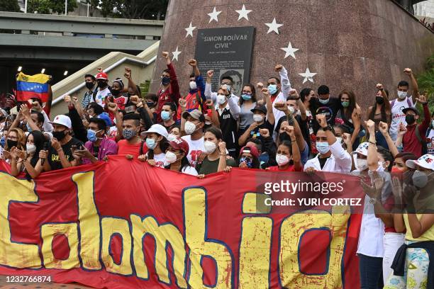 Venezuelans shout slogans and raise their fists as they participate in an act of solidarity with the Colombian people at Bolivar Avenue, in front of...