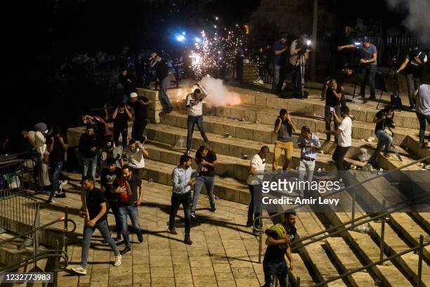 Palestinians escape from a stun grenade fired by Israeli police officers during clashes at Damascus Gate during the holy month of Ramadan on May 8,...