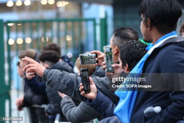 Manchester City fans take photos as the team buses depart at Etihad Stadium. Fans had gathered in anticipation of winning the Premier League title,...