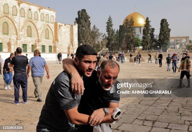 Palestinianman helps a wounded fellow protester amid clashes with Israeli security forces at Jerusalem's Al-Aqsa mosque compound on May 10 ahead of a...