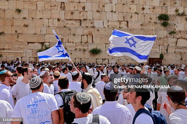 Jewish men wave Israeli flags as they gather at the Western Wall, the holiest site where Jews are allowed to pray, in the old city of Jerusalem on...