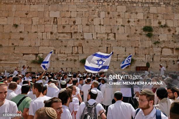 Jewish men wave Israeli flags as they gather at the Western Wall, the holiest site where Jews are allowed to pray, in the old city of Jerusalem on...