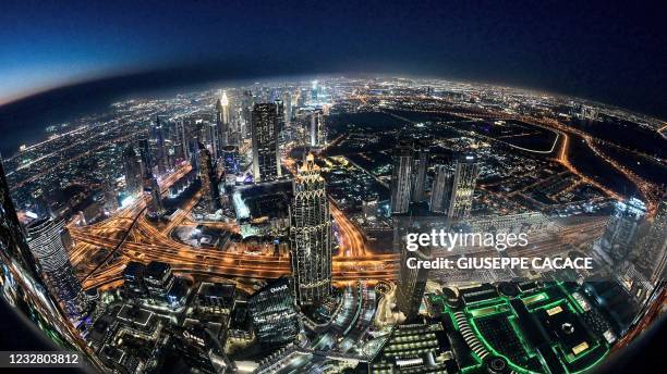 This picture taken with a fish-eye lens on May 9, 2021 shows a view of the Dubai city skyline as seen from the Burj Khalifa, currently the world's...