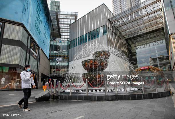 Man wearing a face mask checks his mobile phone while walking along an empty shopping mall area. Malaysias Prime Minister Muhyiddin Yassin has...