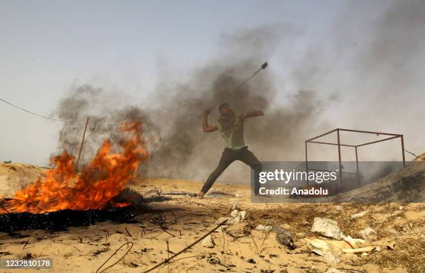 Palestinian burns tires and uses a slingshot to throw a stone on interventions of Israeli forces during a demonstration to protest attacks by Israeli...