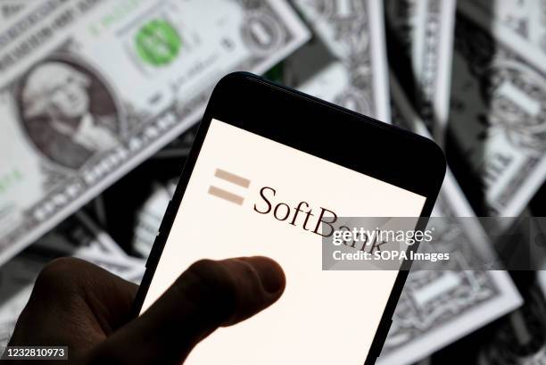 In this photo illustration the Japanese multinational holding conglomerate SoftBank logo seen displayed on a smartphone with USD currency in the...