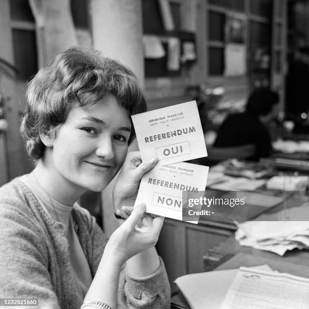 Young woman shows, on March 26, 1962 in Paris, two "yes" and "no" ballots between which voters will have to choose during the self-determination...