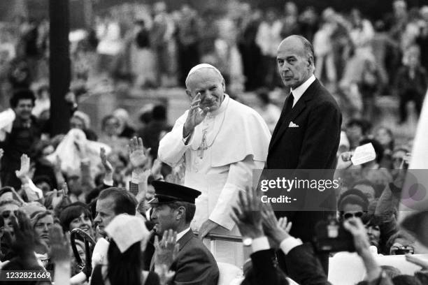 Pope John Paul II waves to the crowd in Paris next to French President Valery Giscard d'Estaing during his official visit in France on May 30, 1980.