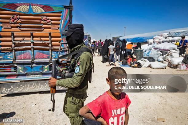 Boy stands next to a member of Kurdish security amid preparations for departure as another group of Syrian families is released from the Kurdish-run...
