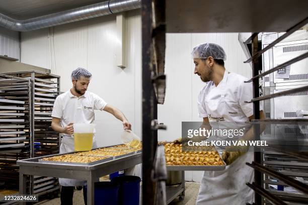 Employees prepare baklava and other sweets at an artisan Turkish delicatessen in Haarlemmermeer, a municipality of Amsterdam on May 11, 2021. -...