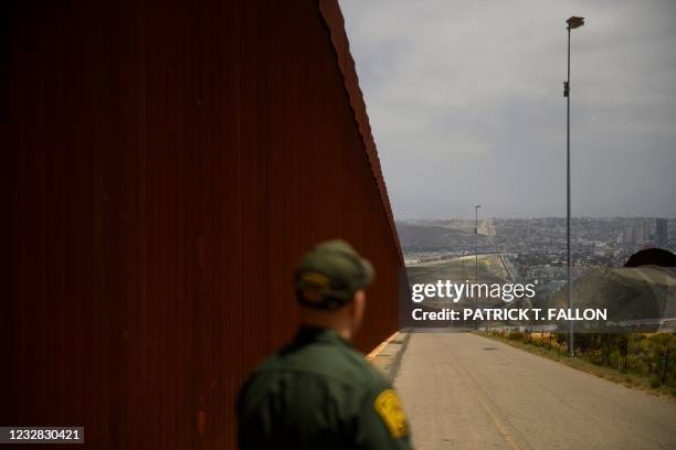 Border Patrol agent looks back towards the San Ysidro port of entry while standing next to a new section of the steel bollard-style border wall along...