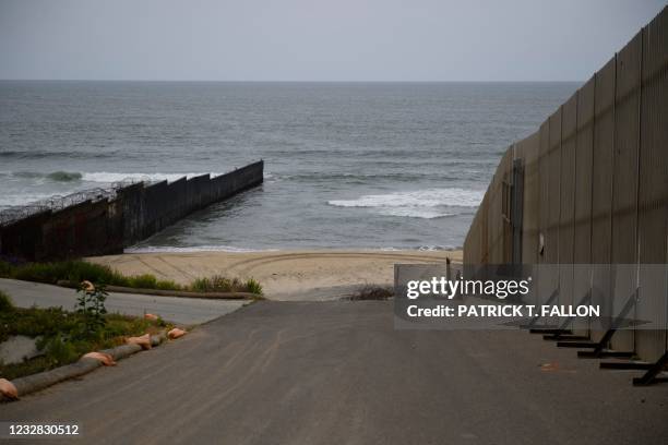 The border wall crosses the beach as it ends in the Pacific Ocean along the US-Mexico border between San Diego and Tijuana on May 10, 2021 at...