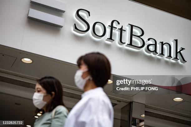 Pedestrians walk past a logo of the SoftBank Group in Tokyo on May 12, 2021.