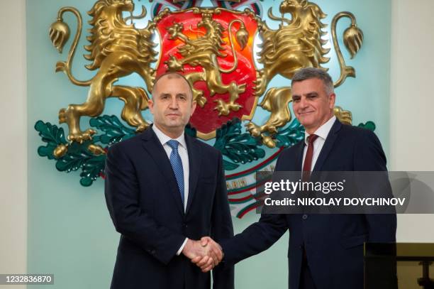 The newly appointed caretaker Prime Minister Stefan Yanev shakes hands with Bulgarian President Rumen Radev during an official ceremony at the...