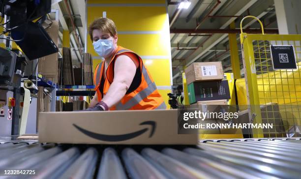 An employee prepares a package for shipment at the Amazon logistics centre in Suelzetal near Magdeburg, eastern Germany, on Mai 12, 2021. - The US...