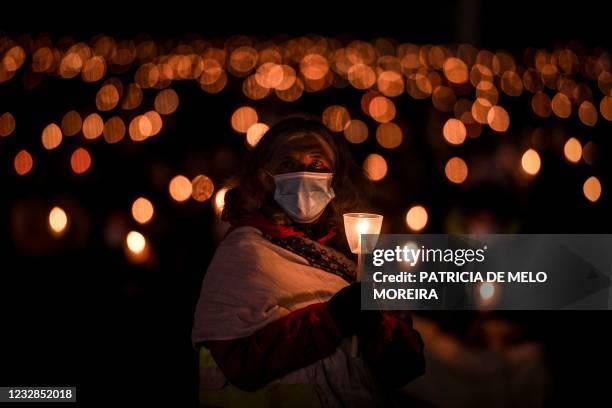 Pilgrim wearing a face mask holds a candle during the annual Fatima pilgrimage at the Fatima shrine in central Portugal held under strict social...