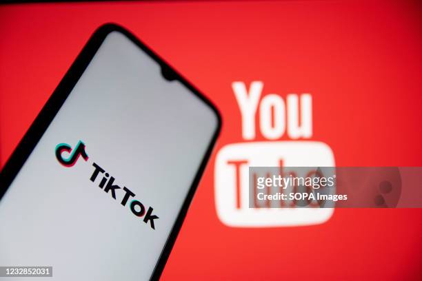In this photo illustration a TikTok logo seen displayed on a smartphone screen with a YouTube logo in the background. YouTube will pay $100 million...