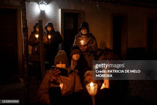 Pilgrims wearing face masks hold candles during the annual Fatima pilgrimage at the Fatima shrine in central Portugal held under strict social...