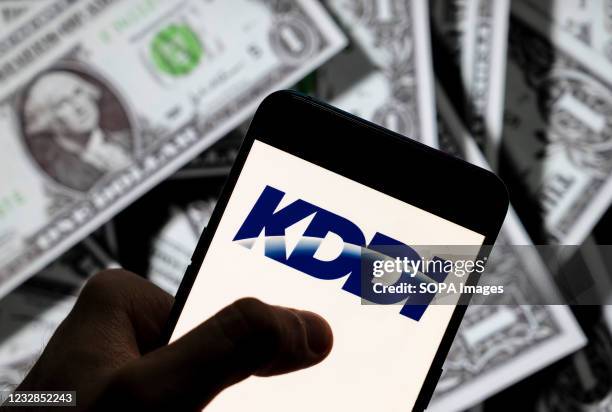 In this photo illustration the Japanese telecommunications operator company KDDI logo seen displayed on a smartphone with USD currency in the...