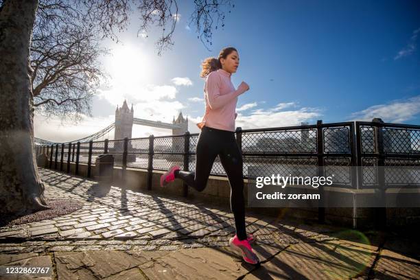 young woman running alone by the river thames - immune system stock pictures, royalty-free photos & images