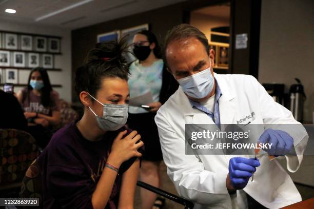 Pharmacist Andrew Mac shows the syringe to Maelani Ben-Ezra 12, to put her her ease before she receives the Pfizer-BioNTech Covid-19 vaccine at the...