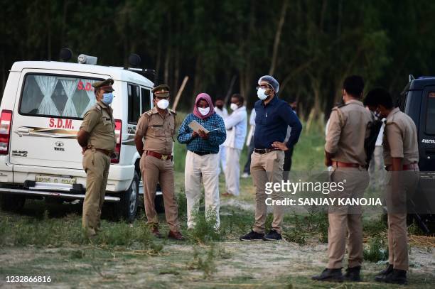 Police and administrative officials inspect a cremation ground on the banks of Ganges River, where suspected bodies of Covid-19 coronavirus victims...